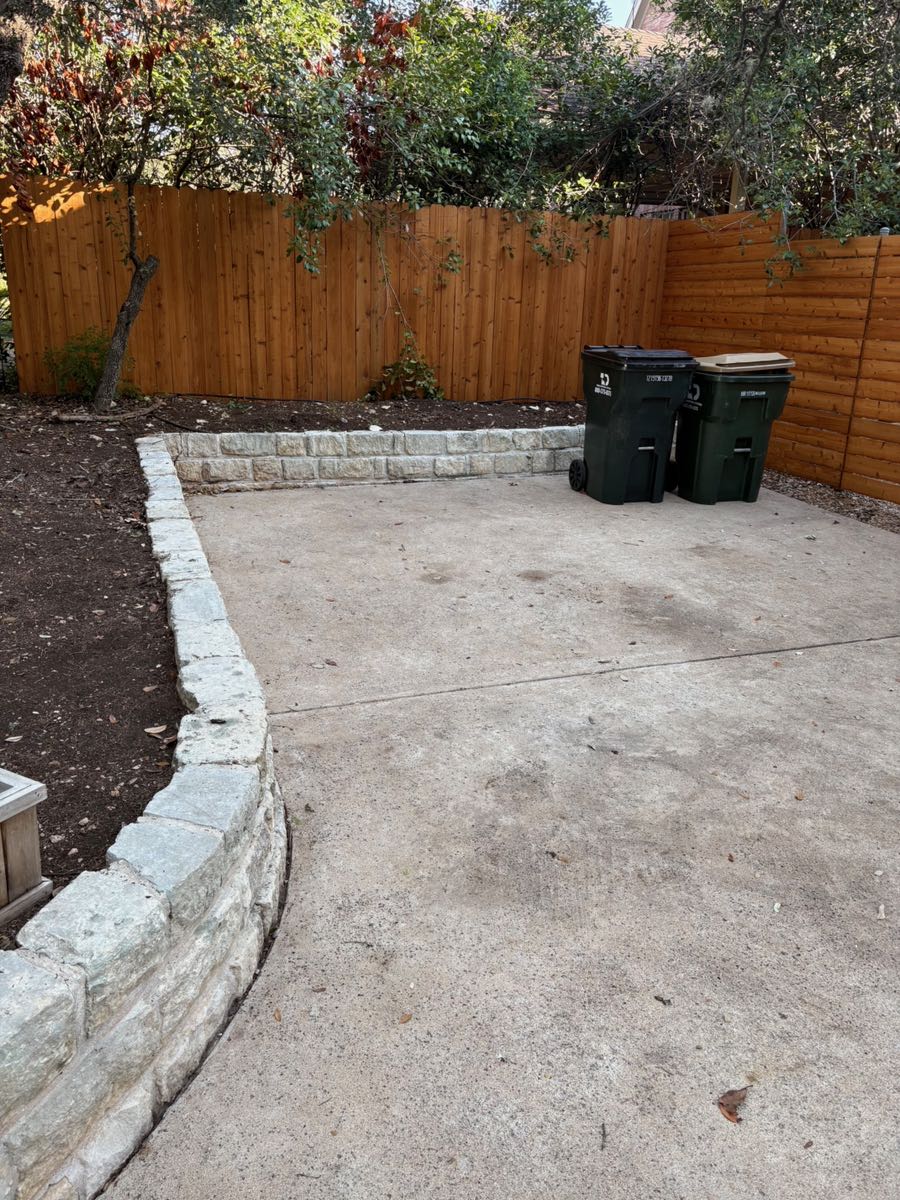 The same patio cleared to clean concrete with only the trash bins left standing
